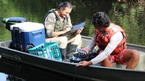FGCU student Ian Lisle tests water temperature while Professor Serge Thomas takes notes