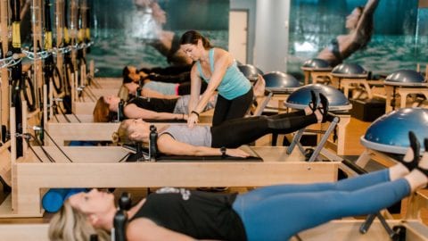 A Club Pilates instructor works with clients