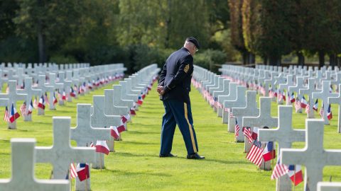 A veteran stands over graves of fellow soldiers at St. Mihiel American Cemetery and Memorial in France