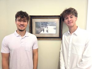 Jeffrey and Matthew stand next to a photo of their younger selves
